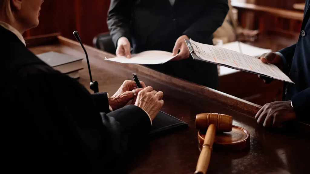 Judge reviewing and signing documents at the bench with a gavel nearby